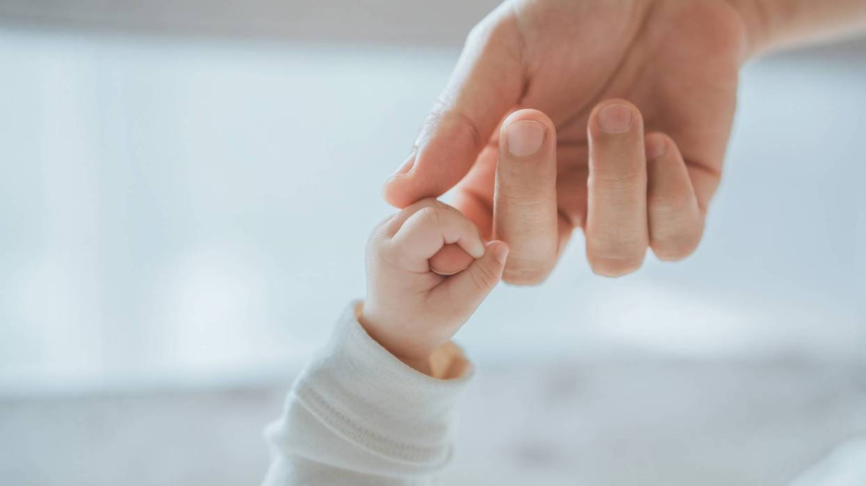 Close-up little hand of child baby holding hand of mother, A newborn holds on to mom's, dad's finger, Love and relationship with infant, Care and support, Dreaming and protection