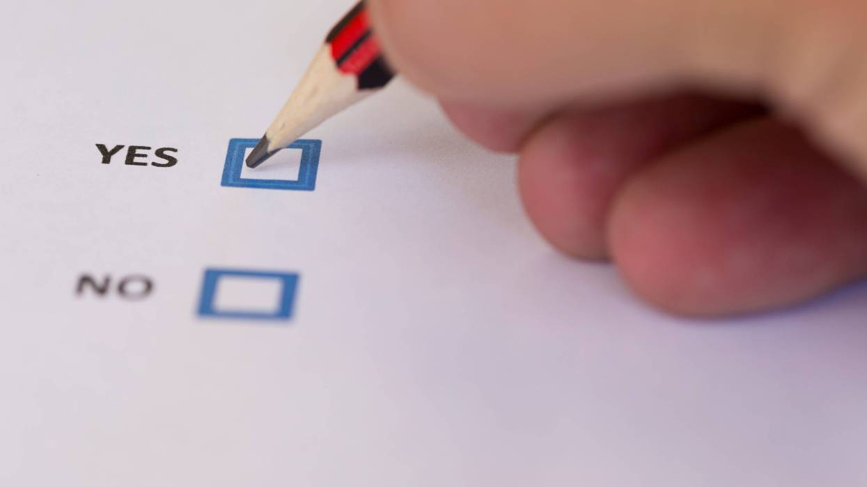 Close up of a hand marking a voting slip with a yes vote