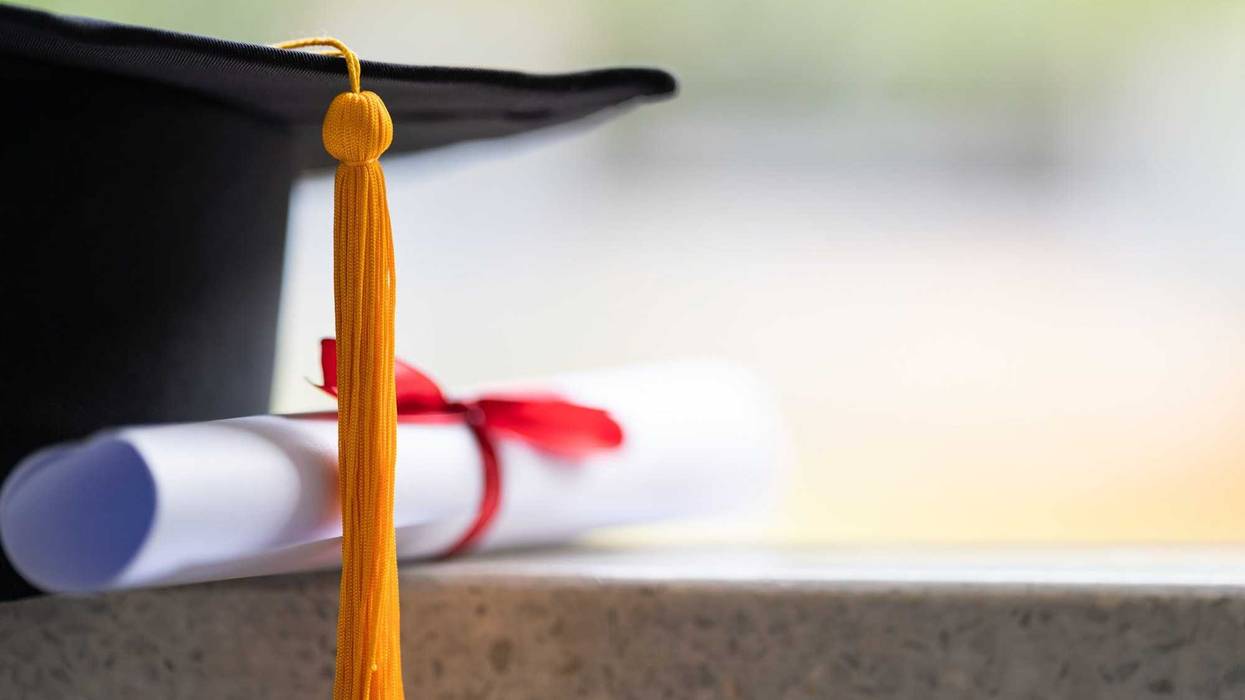 Close-up of a mortarboard and degree certificate put on the table. Education stock photo