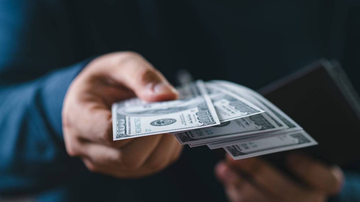 Close-up of a person handing over US dollar bills.