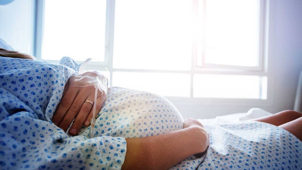 Close-up of a pregnant woman's belly in a hospital bed.