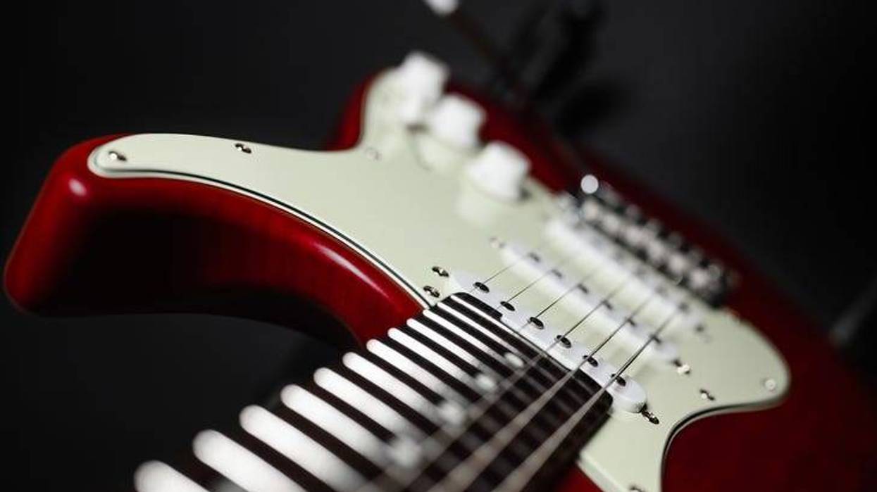 Close-up of a red electric guitar on a black background