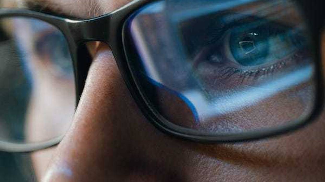 Close up of computer screen reflecting off eyeglasses