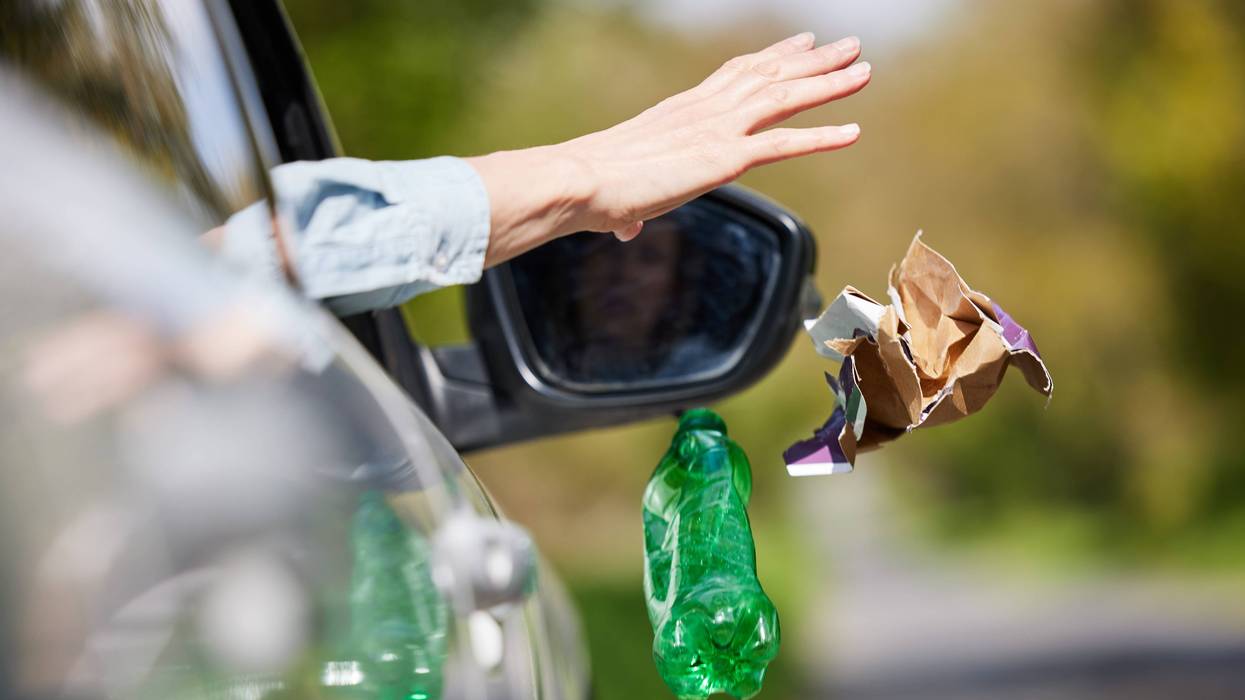 Close Up Of Driver In Car Dropping Trash Out Of Window