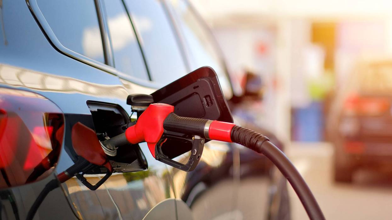Close-Up of Fuel Nozzle Refueling Black Car at Gas Station During Sunset