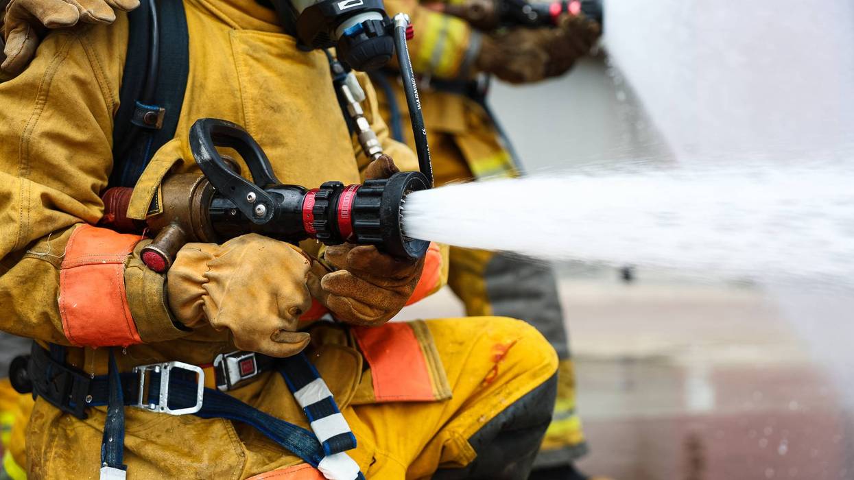 Close up of hand Firefighter high pressure spraying water to stop fire.