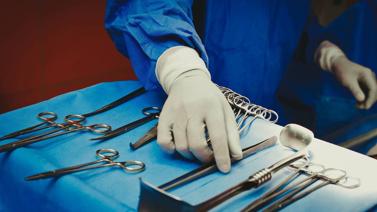 Close-up of hand holding surgical instruments in the operating room, Surgical tools lying on the table