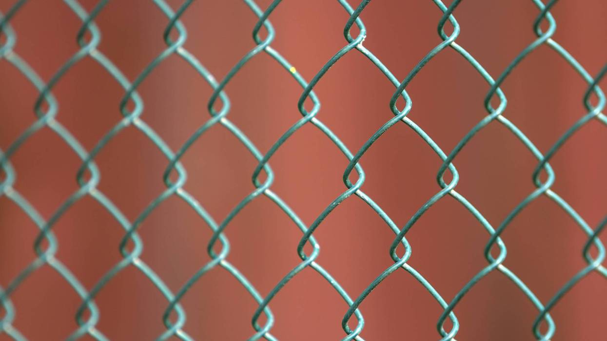 Close-up of isolated painted simple geometric black iron metal wire chain link fence eon dark red background. Fence, protection and enclosure concept.