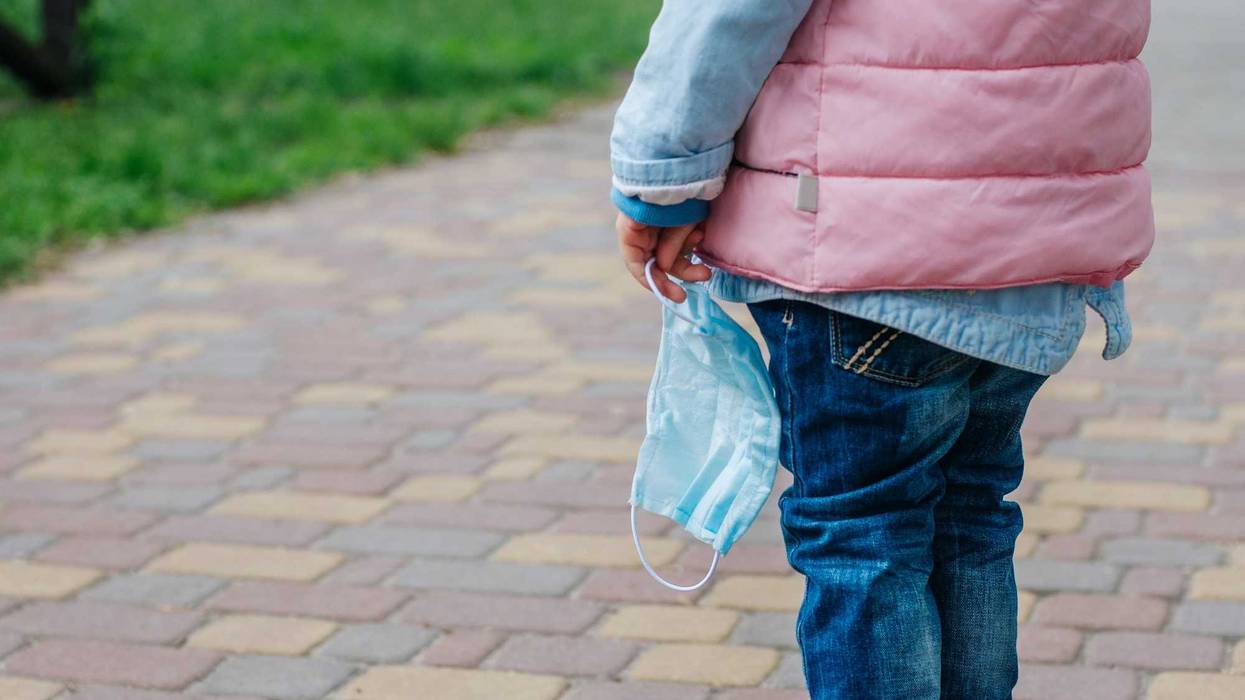 Close up of little girl holding protective face mask outside