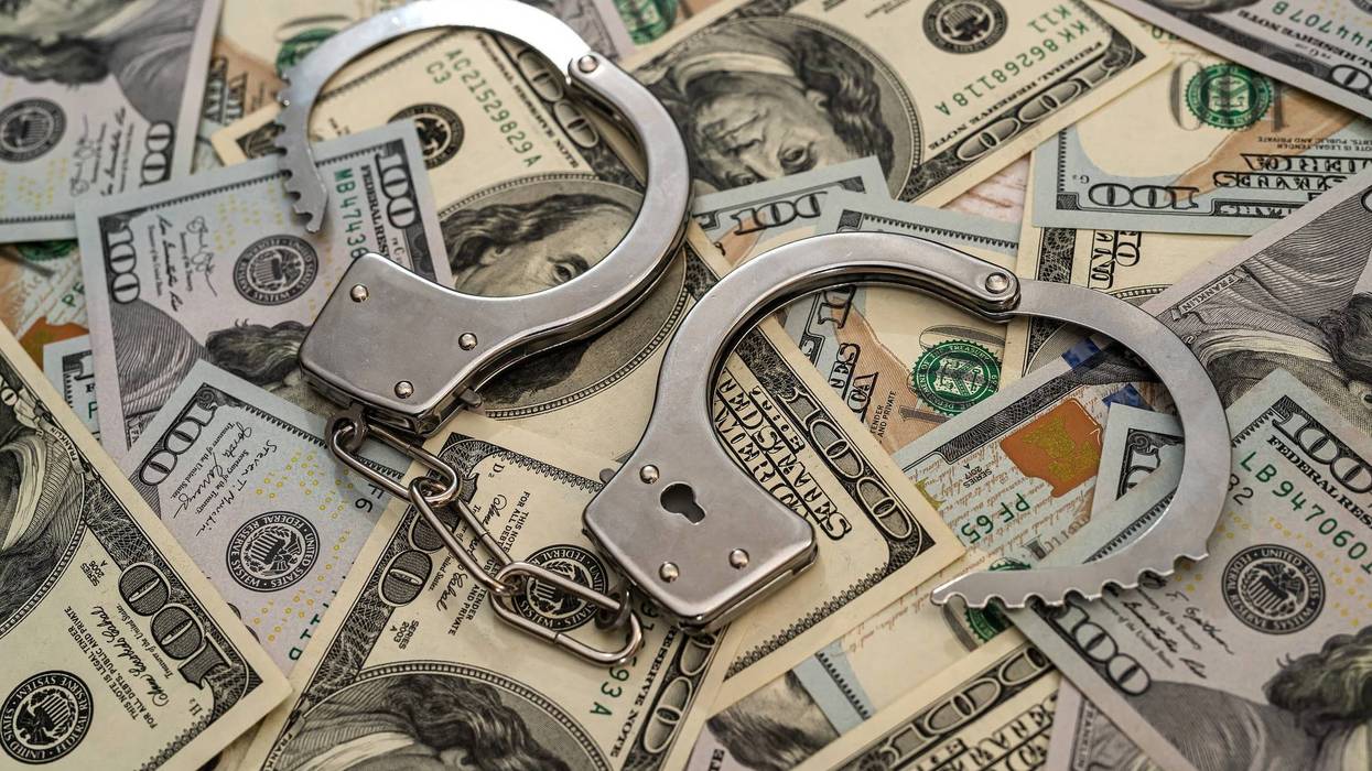 close up of metal handcuffs on hundred dollar banknotes