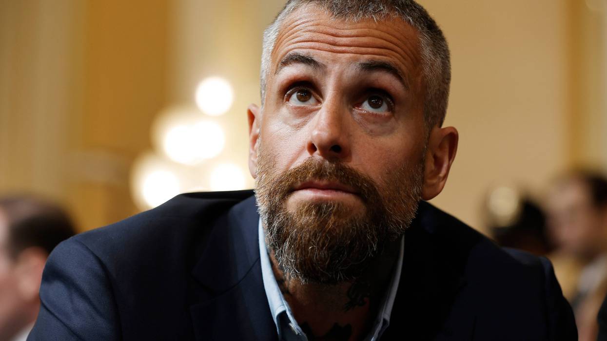 close up of michael fanone. he has short gray hair and a gray and brown goatee and wears a black suit