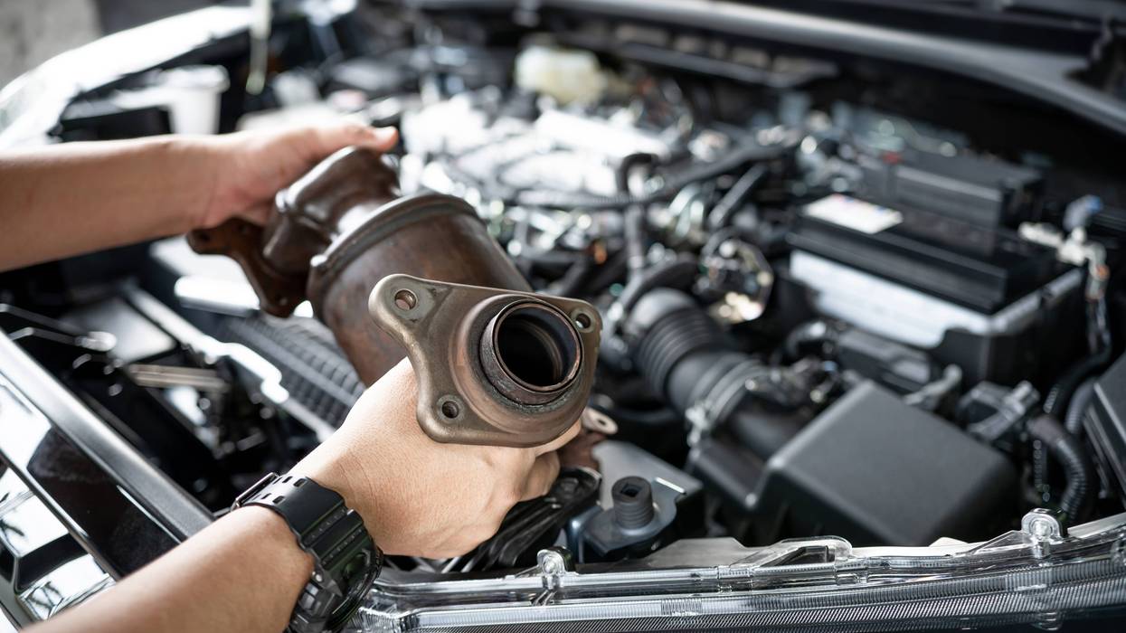 Close-up of old catalytic converter in man's hands