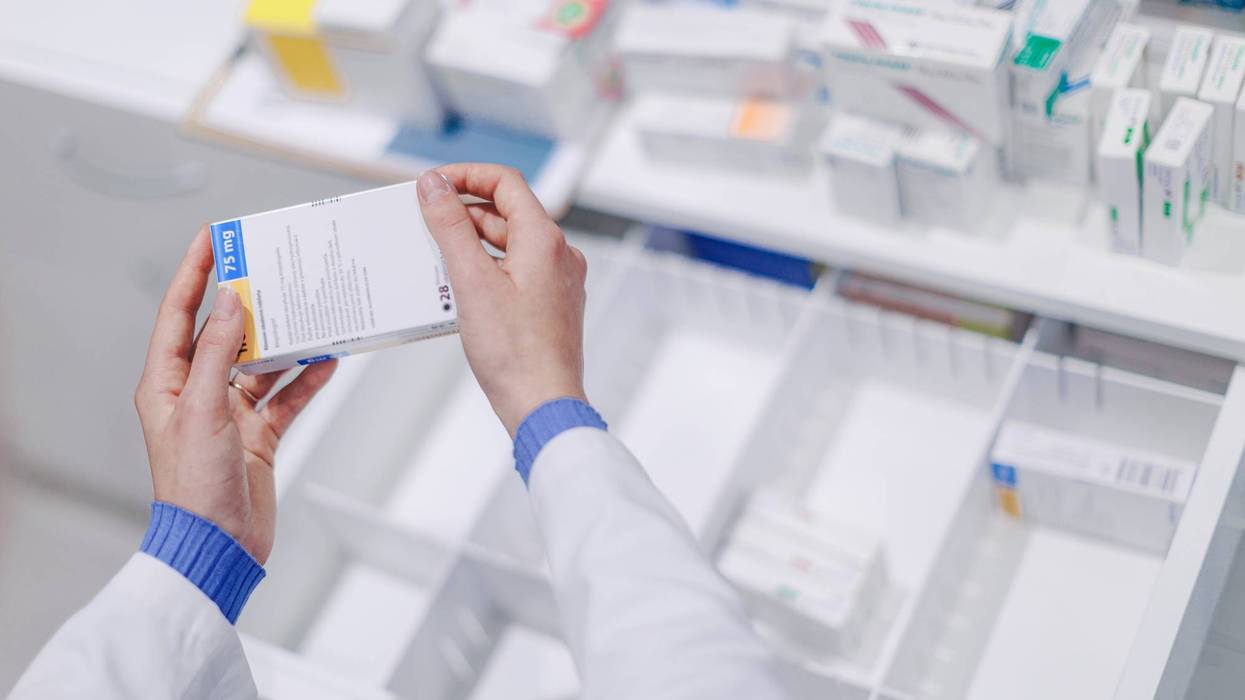 Close-up of pharmacist holding medicines in a pharmacy.