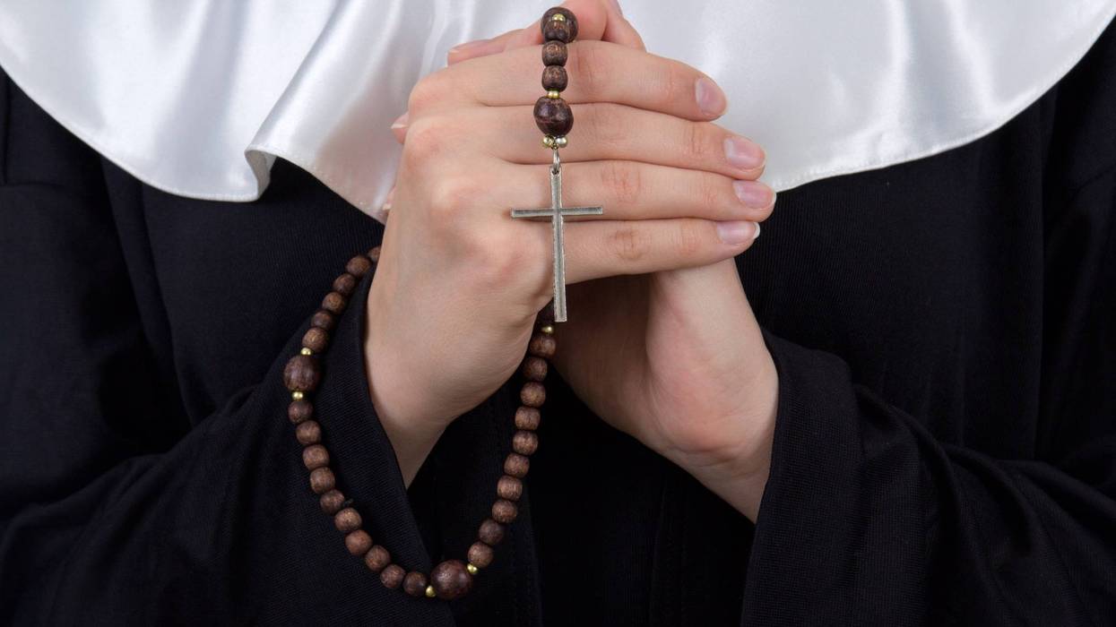 close up of rosary in female nun hands