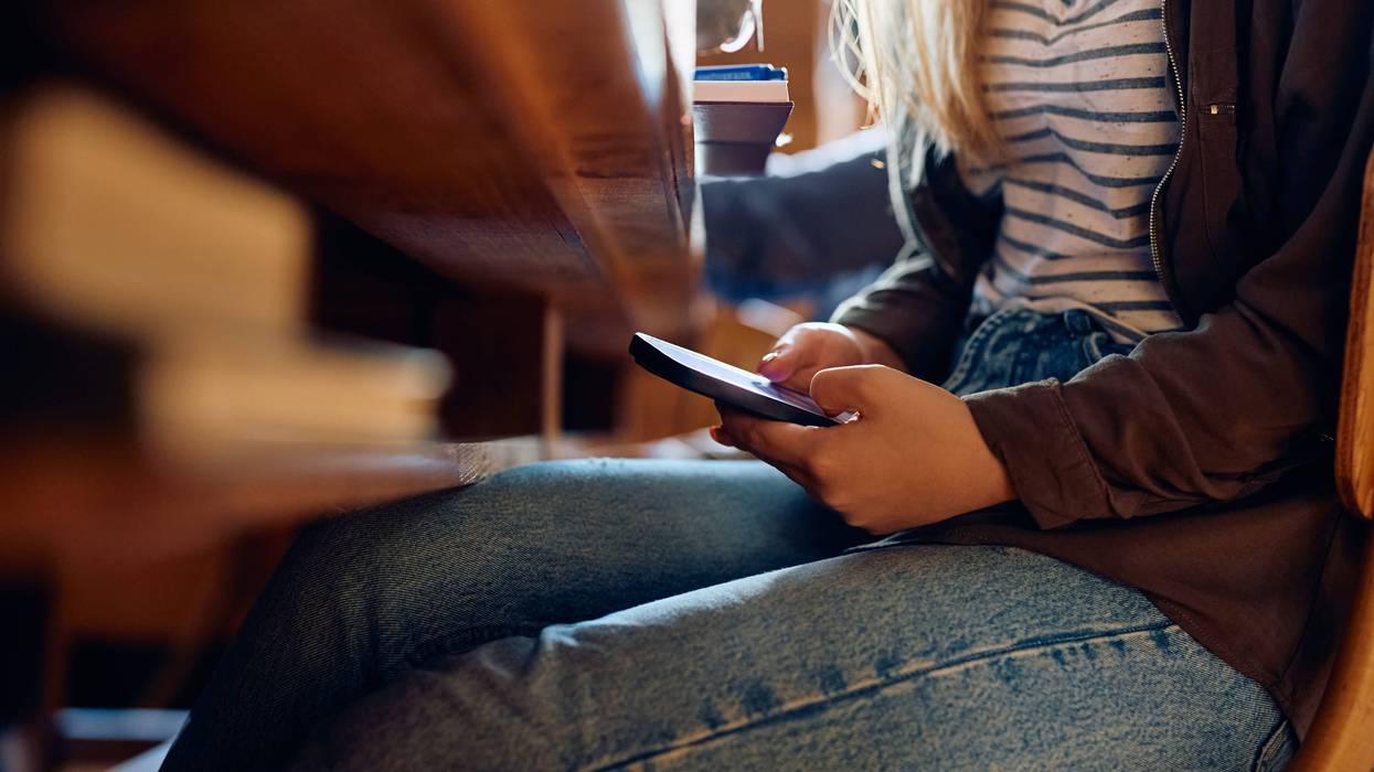 Close-up of student using a cell phone in class