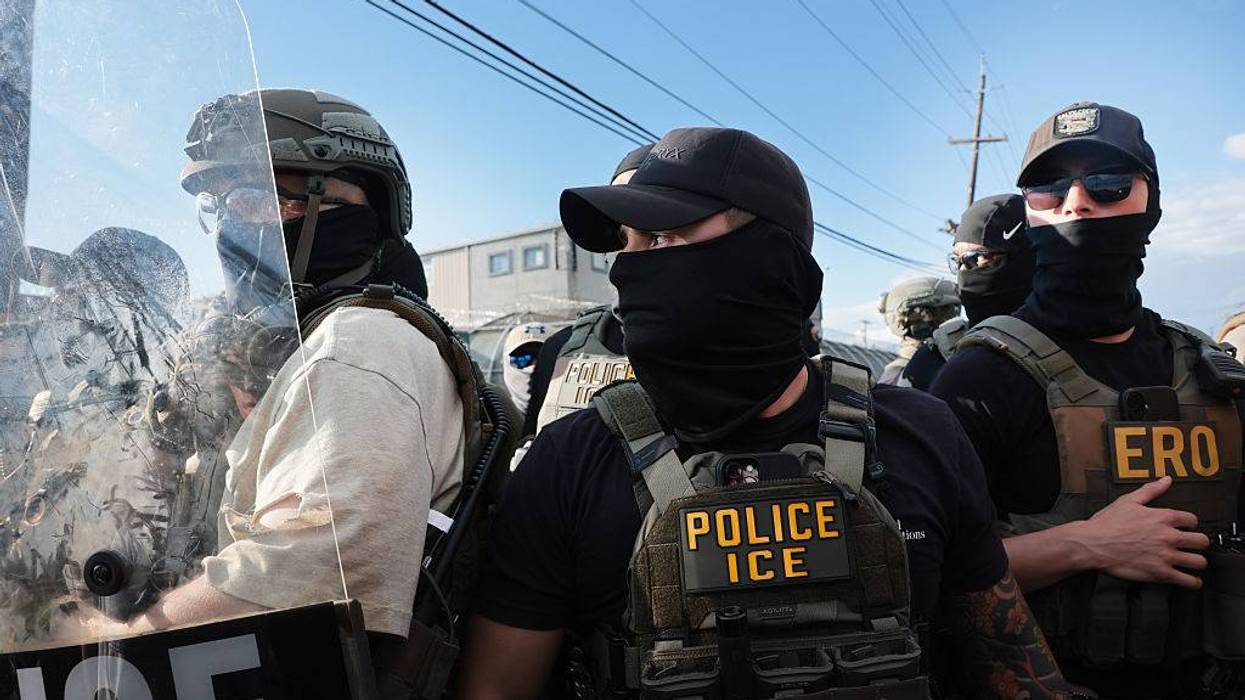 Close-up of tactical ICE and ERO officers in vests and face coverings, one with a shield showing 'ICE'.