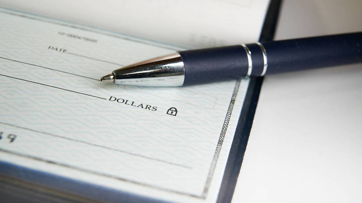 Close-Up view of a pen resting on a blank check on a desk