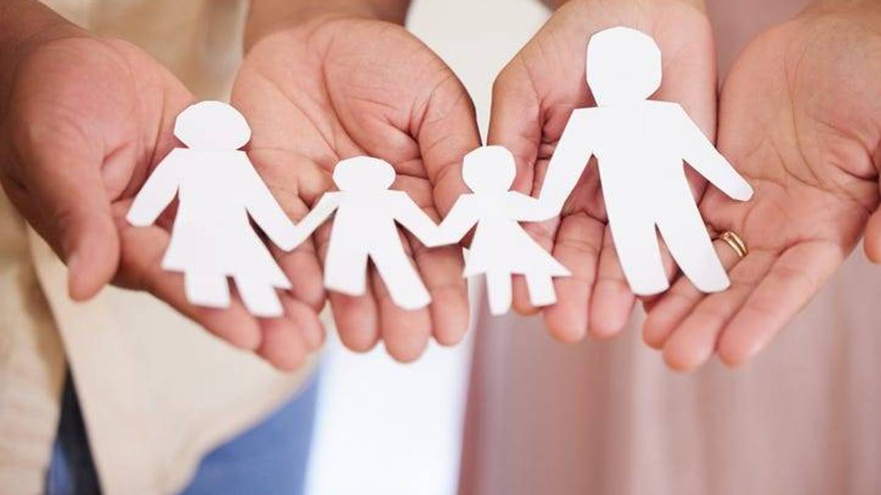 Closeup of a couples hands holding paper cutout of a perfect family. Symbol of home cover, insurance, health, adoption, custody, law, safety, security protection, foster, adoption family home concept