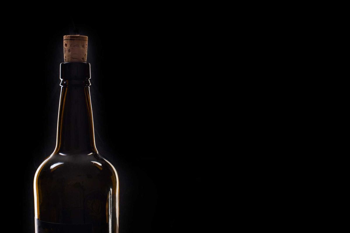 Closeup of an opening of a wine bottle with cork in front of black background with text field. Macro.