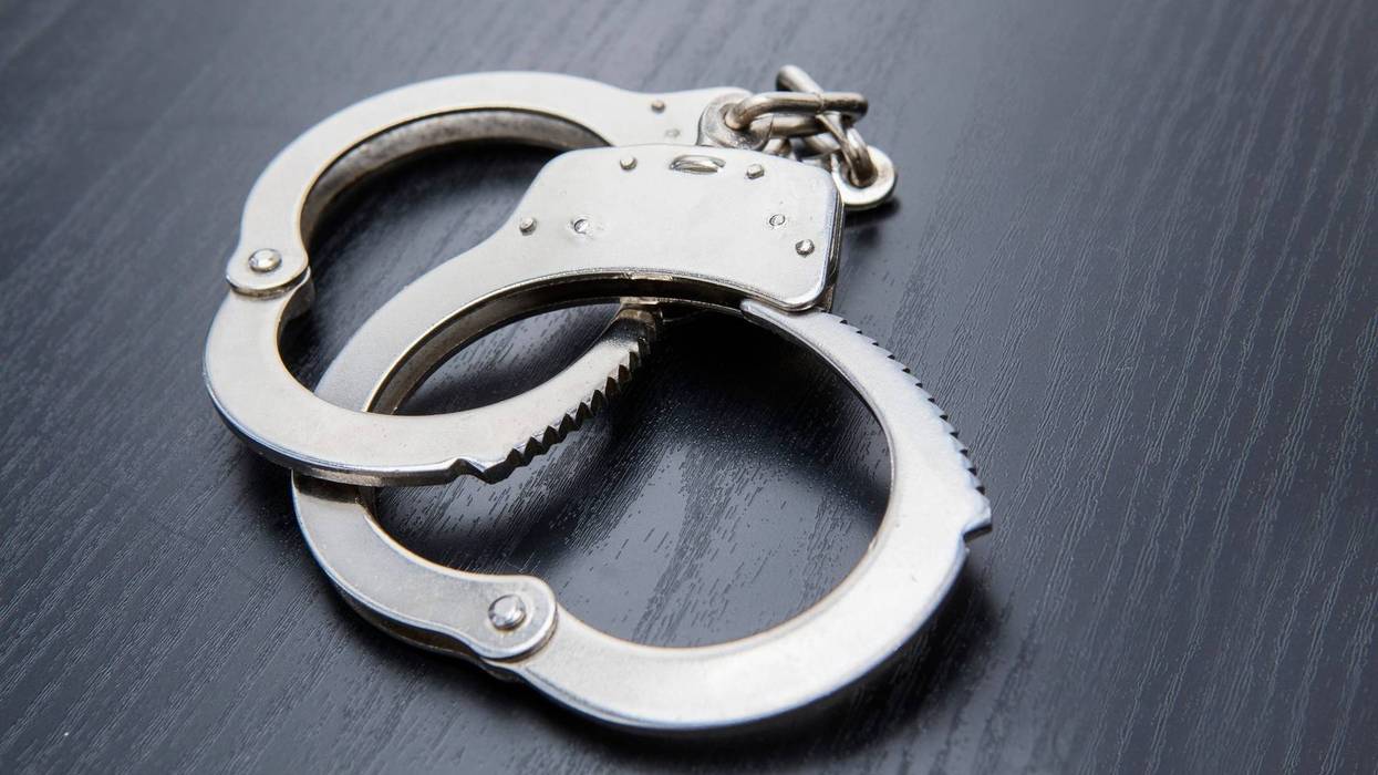 Closeup of silver handcuffs detaining crime prisoners. Shot on the wooden table