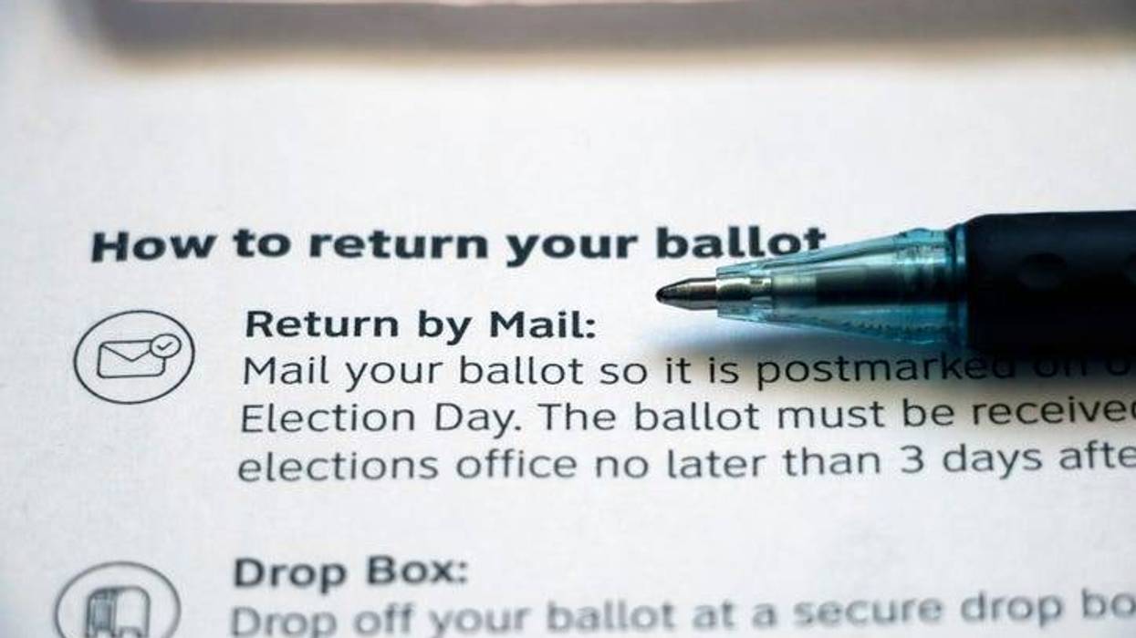 Closeup of vote-by-mail return ballot instructions on an official election mail envelope with pen lying on top.