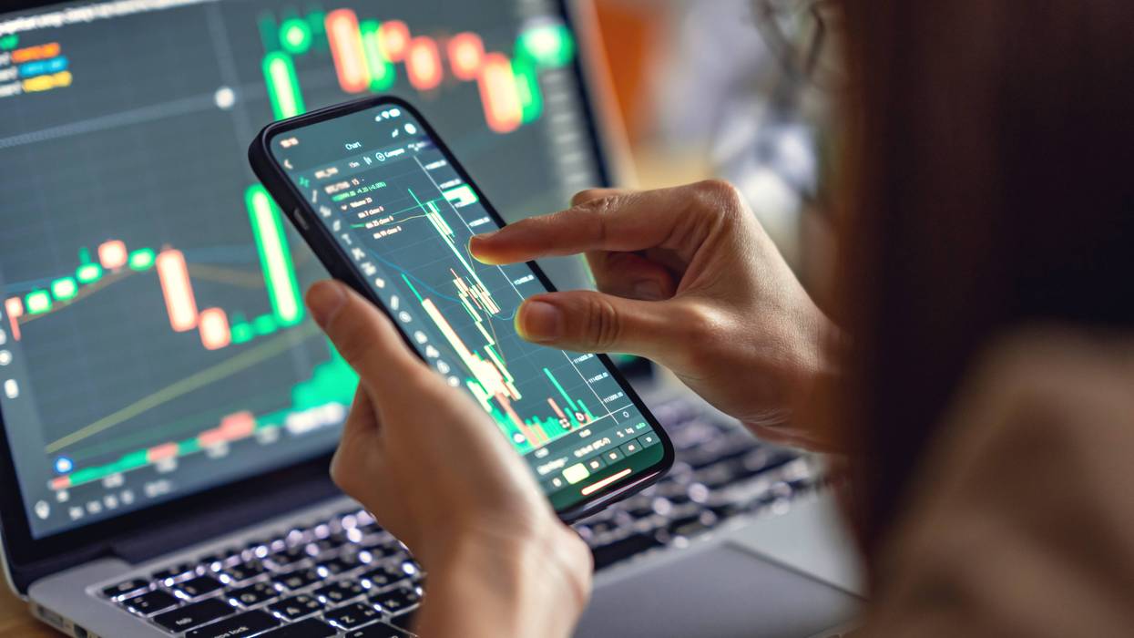 Closeup - Woman is checking Bitcoin price chart on digital exchange on smartphone, cryptocurrency future price action prediction.