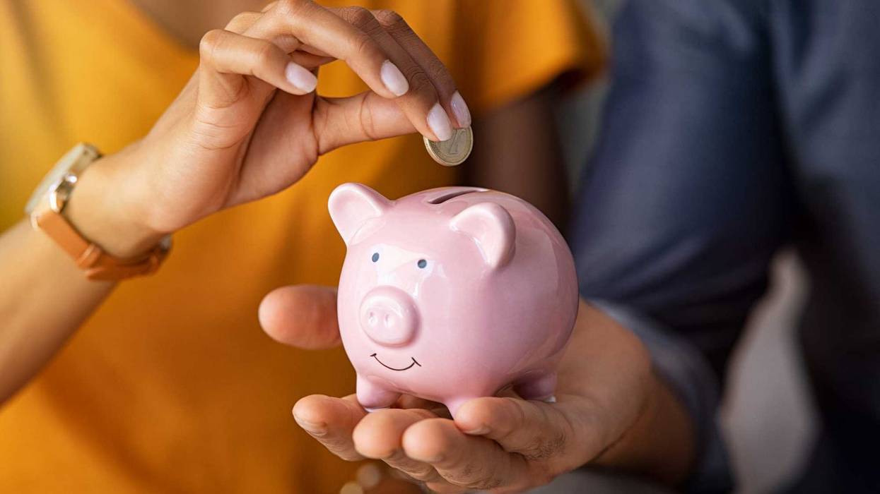 Coin going into piggy bank stock photo.