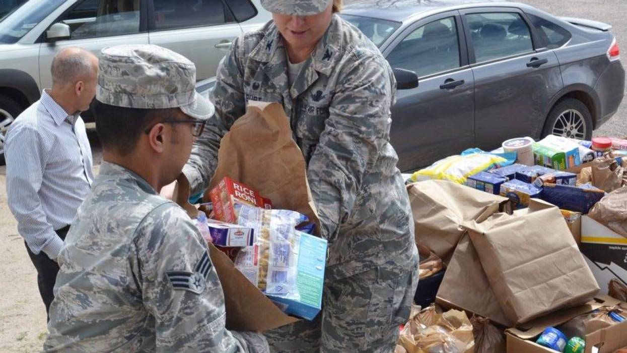 Col. DeAnna Burt, 50th Space Wing commander (right), transfers food to Senior Airman Matthew Sarangay, 50th Contracting Squadron, during a donation drop-off at the Ellicott Helping Hands Food Pantry in Ellicott, Colorado, Tuesday, April 26, 2016.