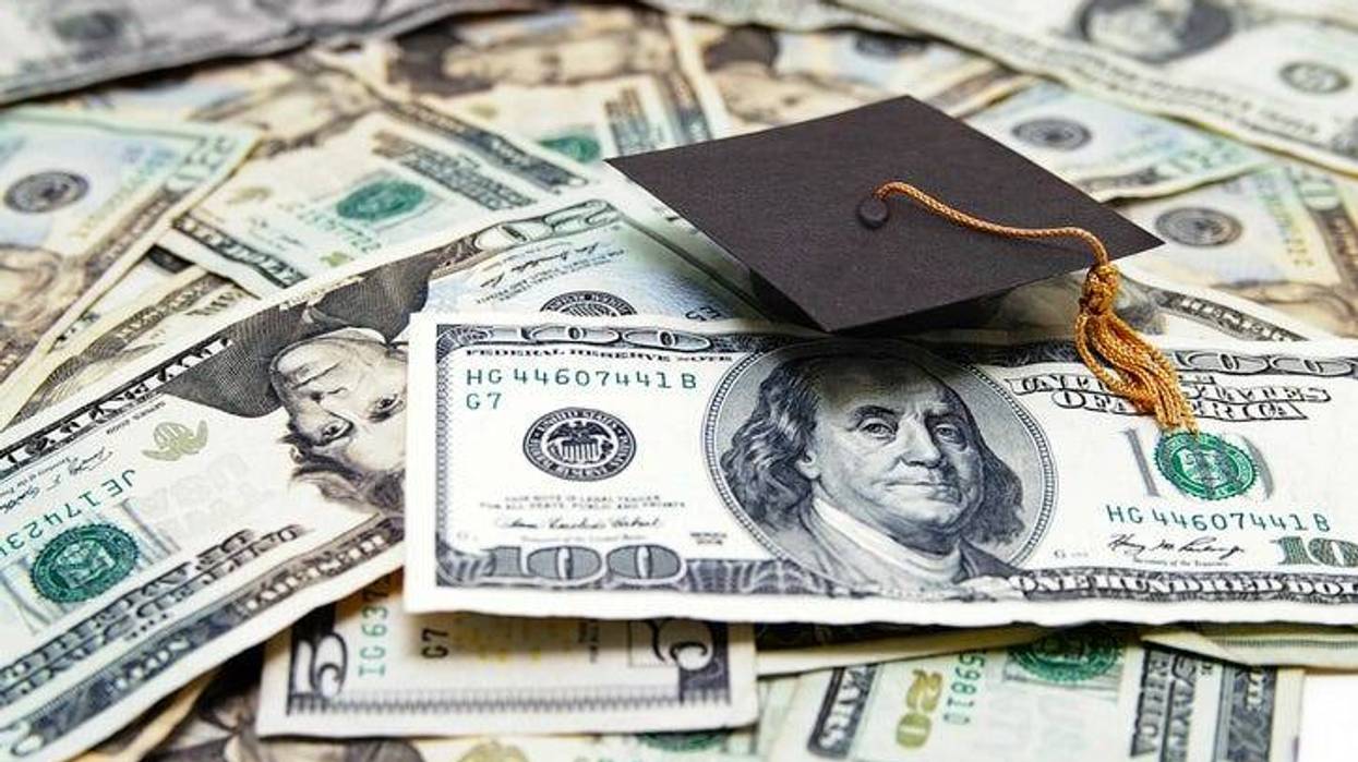 College graduate cap sitting on dollar bills