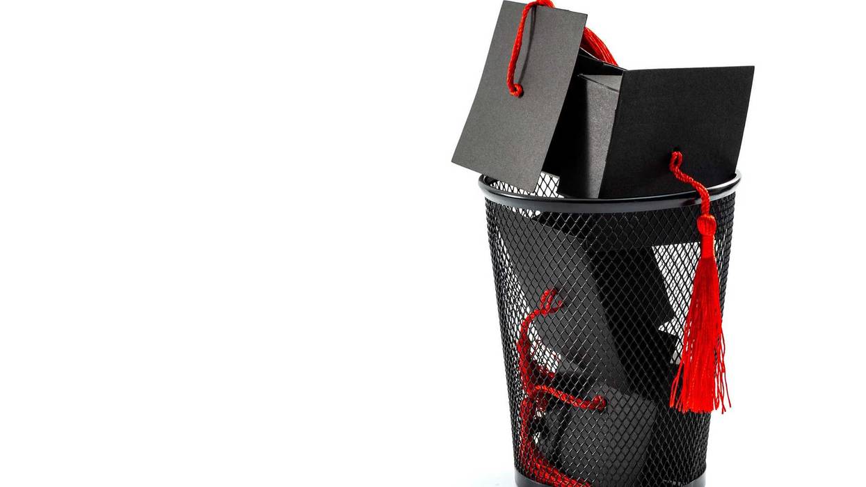 College graduation caps in a trash can.