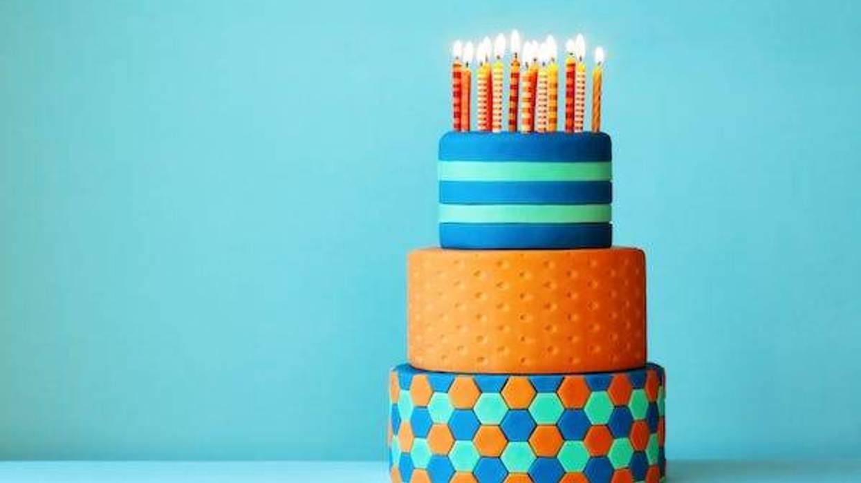 Colorful fondant birthday cake with three tiers and birthday candles