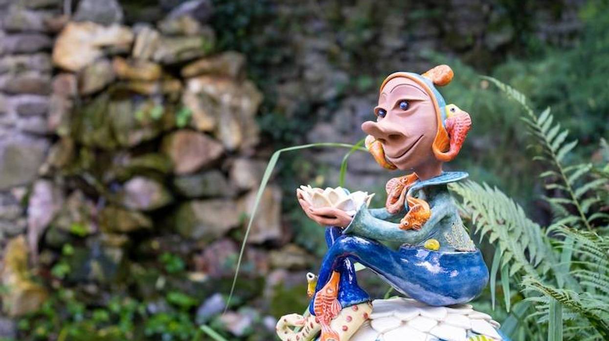 Colorfully painted, ceramic elf statue in a garden