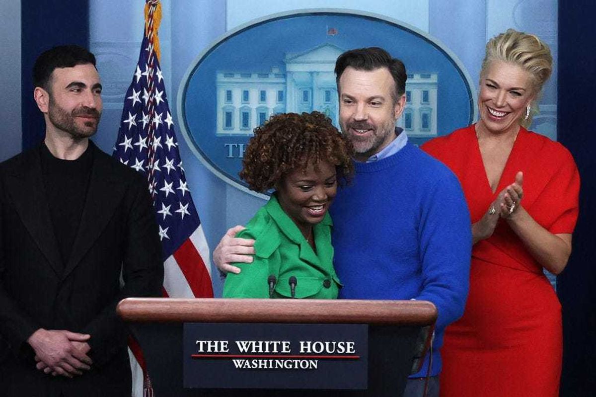 Comedian Jason Sudeikis of the Apple TV+ comedy series Ted Lasso embraces White House Press Secretary Karine Jean-Pierre as other cast members Brett Goldstein (L) and Hannah Waddingham look on during a White House daily news briefing at the James S. Brady Press Briefing Room on March 20, 2023 in Washington, DC. Sudeikis and the cast of Ted Lasso are at the White House to meet with President Joe Biden and first lady Jill Biden to discuss “the importance of addressing your mental health to promote overall well-being.” (Photo by Alex Wong/Getty Images)