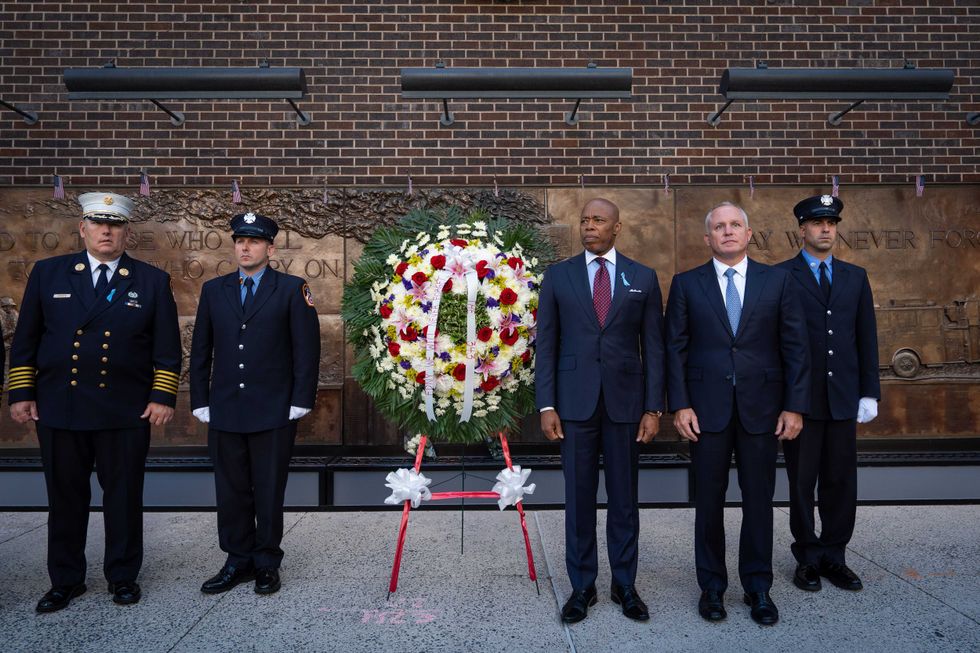 Commissioner of the FDNY Robert S. Tucker (2nd from right) and Mayor Eric Adams observe a moment silence at the FDNY memorial wall on Sept. 11, 2025