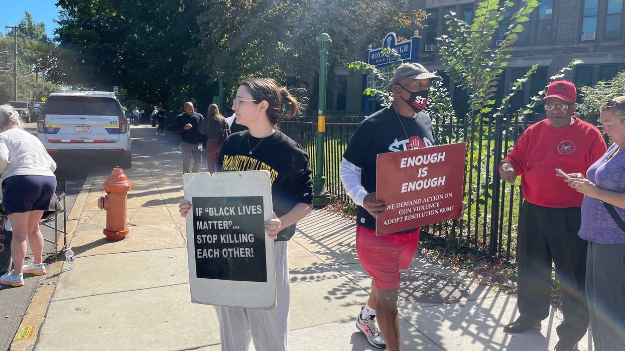 Community members carried signs outside Roxborough High Wednesday in a protest organized by anti-gun violence advocate Jamal Johnson.