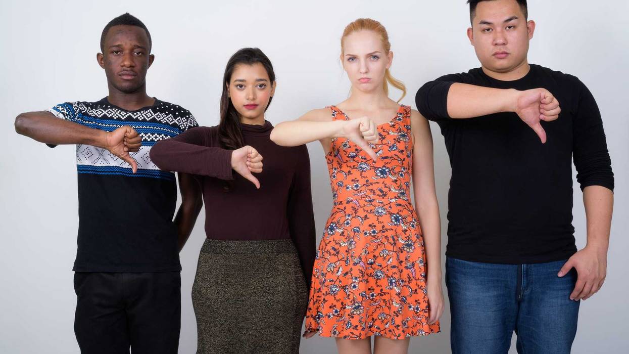 Composition of group of friends over blue blackground looking unhappy and angry showing rejection and negative with thumbs down gesture. Bad expression.