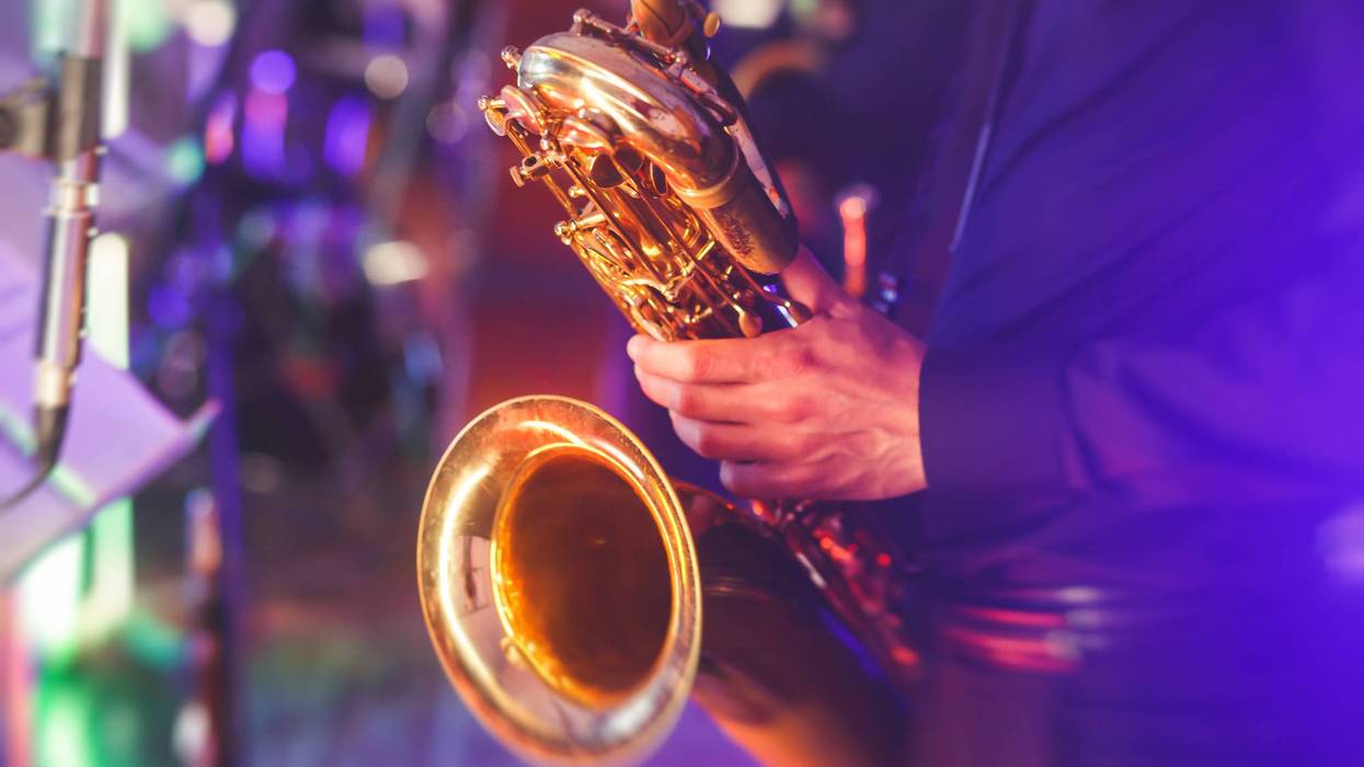 Concert view of a saxophone player with vocalist and musical jazz band in the background