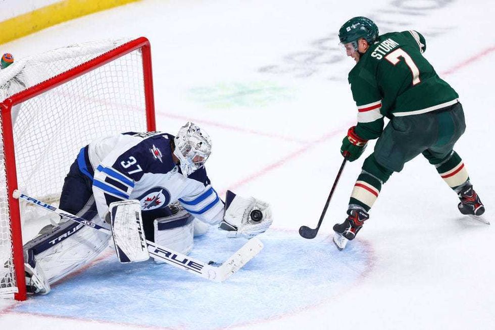 Connor Hellebuyck #37 of the Winnipeg Jets makes a save on a shot by Nico Sturm #7 of the Minnesota Wild during the third period at Xcel Energy Center on October 19, 2021 in St Paul, Minnesota.
