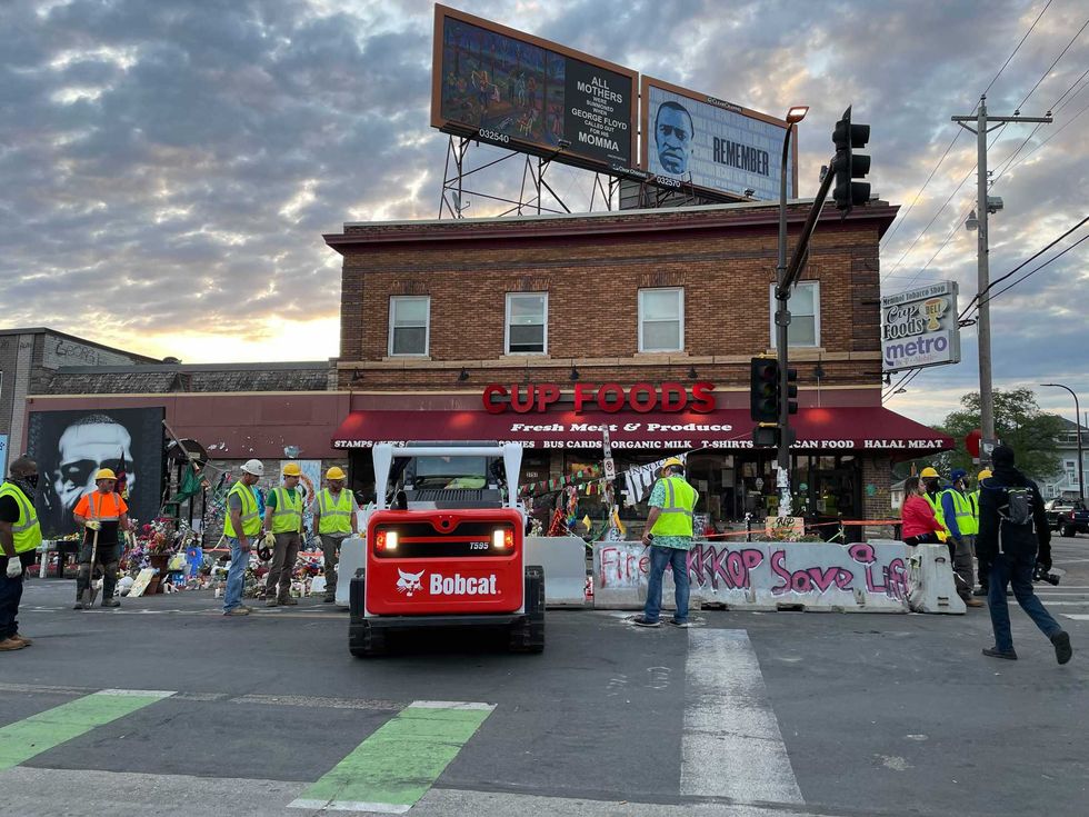 Construction workers bring equipment to begin to tear down George Floyd Square.