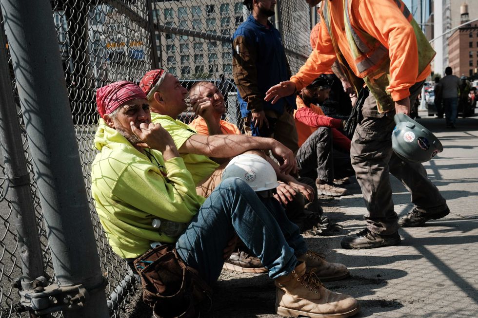 Construction workers rest at the scene of a crane collapse