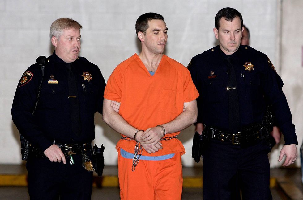 Convicted murderer Scott Peterson is escorted by two San Mateo County Sheriff deputies as he is walked from the jail to an awaiting van March 17, 2005 in Redwood City, California.