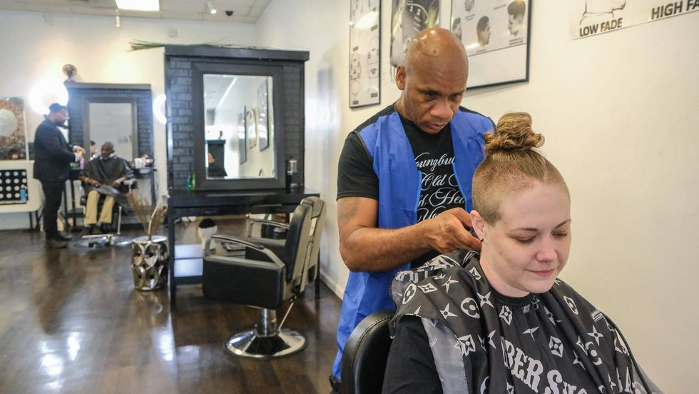 Corey Blackwell gives Genevieve Blankley a trim at Generations Barber Academy.