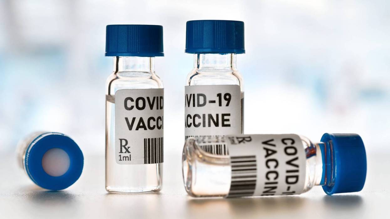 Coronavirus Covid-19 vaccine concept - small glass vials with blue caps on white table, closeup detail (own design - dummy bar code)