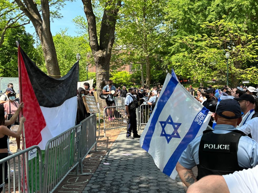 Counter-protesters stand outside the fence of the pro-Palestinian encampment protest at the University of Pennsylvania