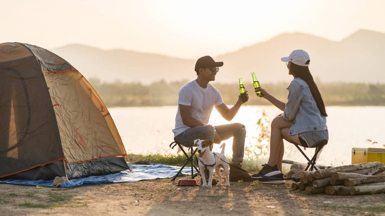 Couple Camping With Beer And A Puppy