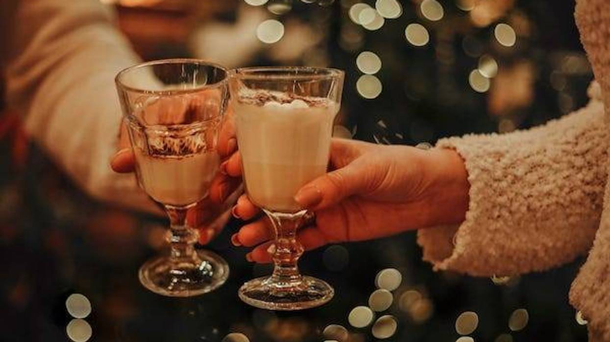 Couple drinking eggnog in front of a Christmas tree