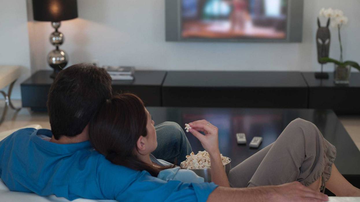 Couple watching television together and eating popcorn