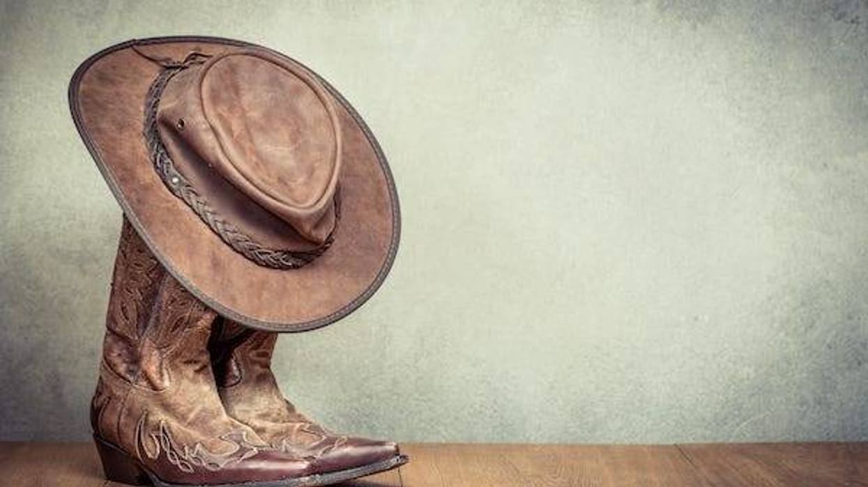 Cowboy boots and hat against concrete wall