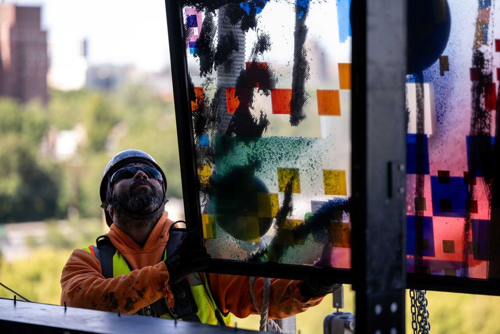 Crews work to install one of 35 stained glass panels for "Uprising of the Sun."