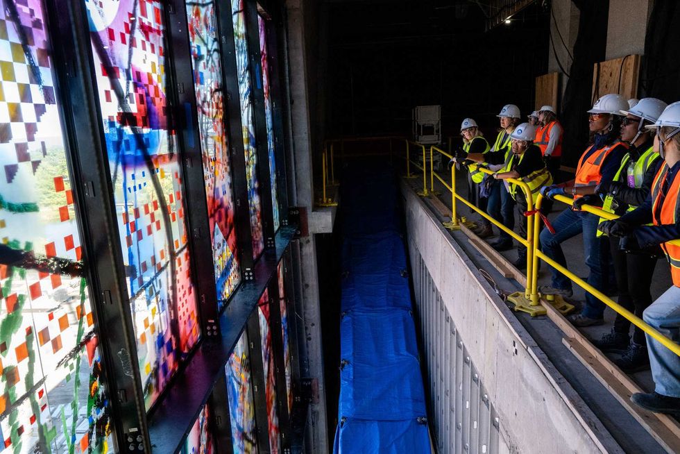 Crews work to install one of 35 stained glass panels for "Uprising of the Sun."